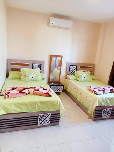 a bedroom with two beds and a mirror at مارينا دلتا Alpha star in ‘Izbat Abū Sulayman