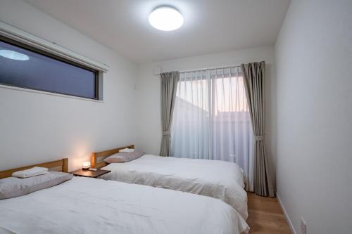 two beds in a hotel room with a window at treehouse - Vacation STAY 22128 in Nagoki