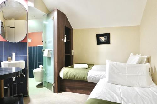 a hotel room with two beds and a bathroom at A Hotel Chinatown in Singapore