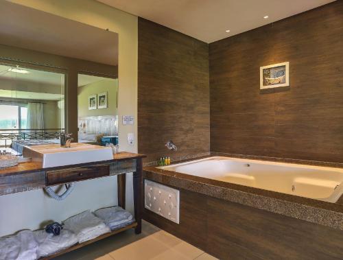 a bathroom with a large tub and a large mirror at Boqueirão Hotel Fazenda in Lages