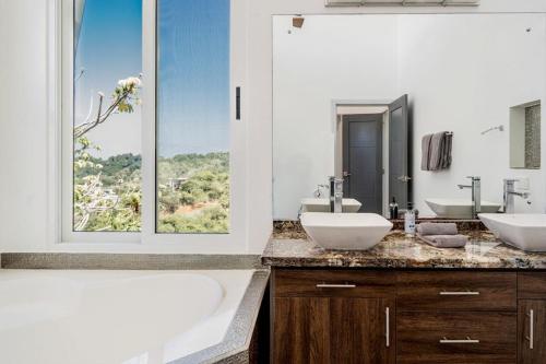 a bathroom with two sinks and a tub and a window at Casa La Cima in Playa Hermosa