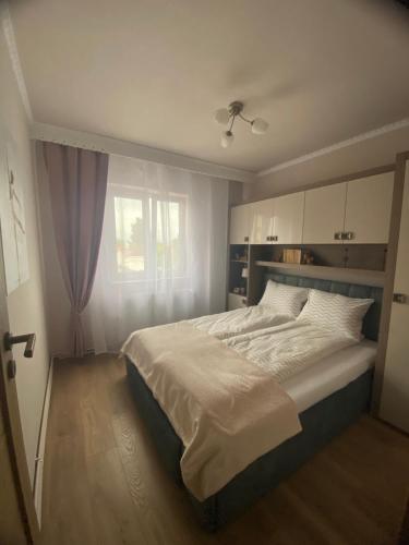 a bedroom with a large white bed with a window at Apartament 29 in Orăştie