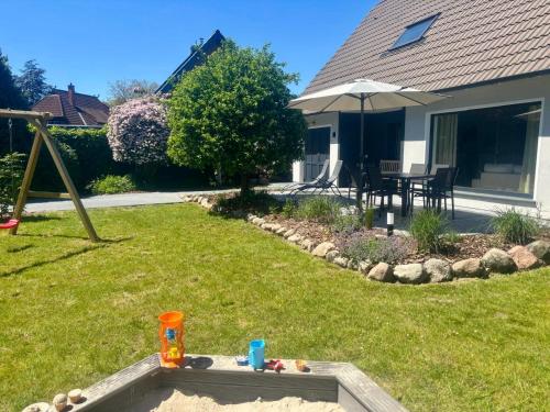 a backyard with a sandbox and an umbrella at Ferienhaus Lykkehus Dümmer See in Hüde