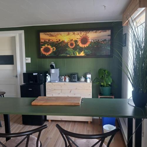 a kitchen with a green wall with a painting of sunflowers at Le nid marin in Gascons