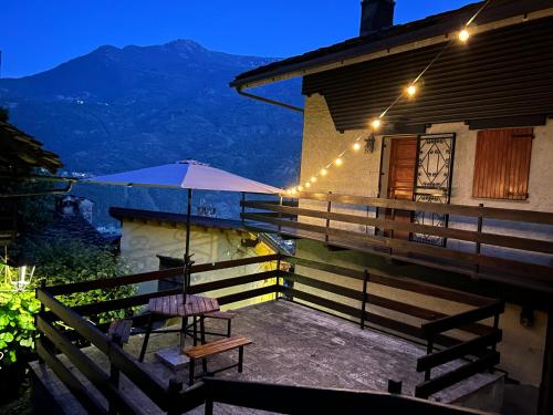 a patio with a table and an umbrella on a house at Casa Vanda in Châtillon