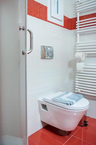 a white toilet in a bathroom with a red floor at Gela in Livadeia