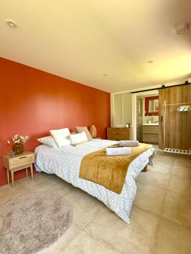 a bedroom with a large bed and a red wall at Villa du lac in Arsac