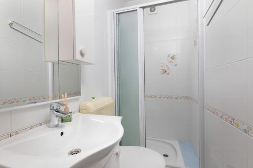 a white bathroom with a sink and a shower at Studio apartman Lea in Baška