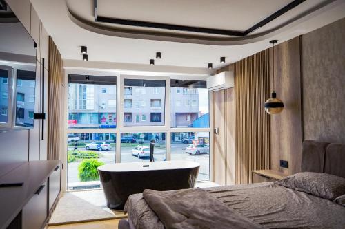 a bedroom with a tub and a large window at AMD LUX apartman in Bijeljina