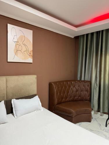 a bedroom with a bed and a chair at Residencial Convênios- Hotelaria e Turismo LDA in Luanda