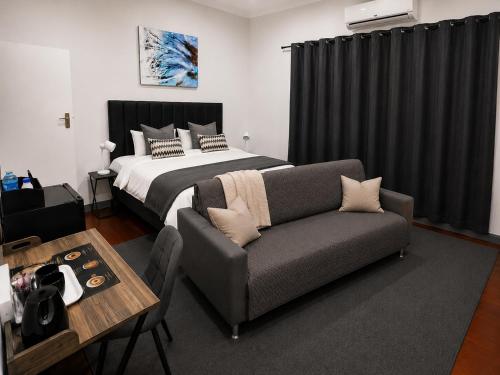 a bedroom with a bed and a couch and a table at 30 on 6th by 306 Accommodation in Bellville