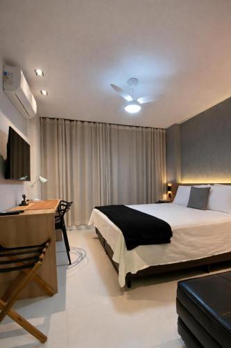 a bedroom with a bed and a desk and a television at Apartamento prox a Arena Niteroi, Uff e Barcas in Niterói