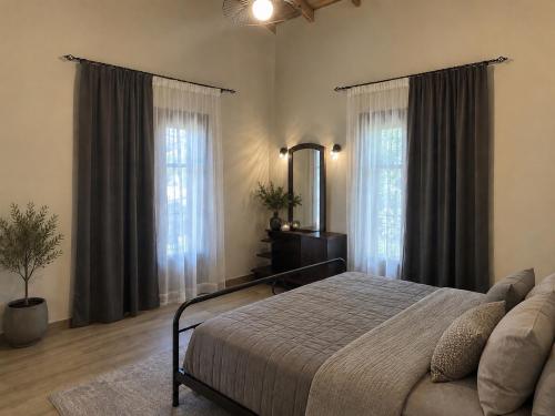 a bedroom with a bed and two large windows at Casa Ortensia in Kato Korakiana