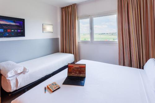 a hotel room with two beds and a laptop on a table at H2 Fuenlabrada in Fuenlabrada