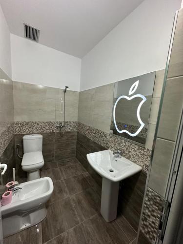 a bathroom with a sink and an apple sign on the wall at Green Berat Villa in Uznovë