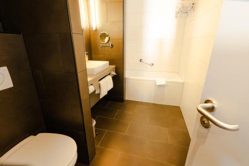 a bathroom with a toilet and a sink and a tub at Stay2Munich Hotel & Serviced Apartments in Brunnthal
