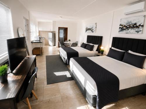 a hotel room with two beds and a desk at 30 on 6th by 306 Accommodation in Bellville