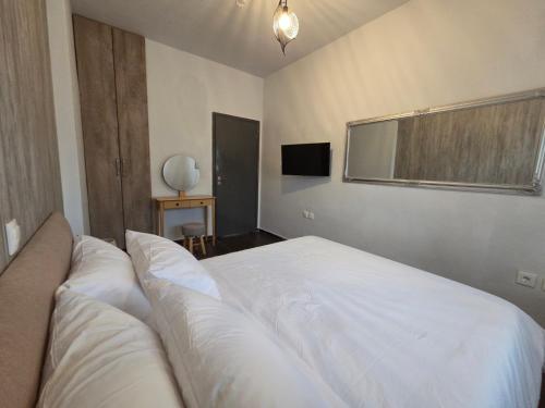 ein Schlafzimmer mit einem weißen Bett und einem Fernseher in der Unterkunft Valla Studio in Rhodos (Stadt)