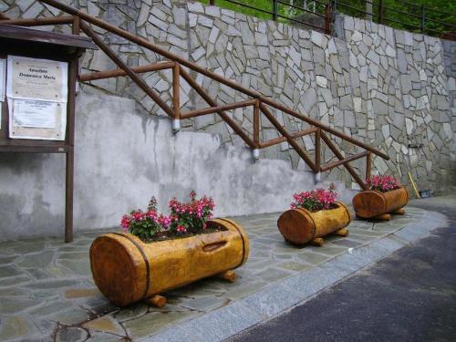 three wooden planters with flowers in them sitting next to a wall at Sotto il Cielo, Balcone panoramico sul borgo di Ingria in Ingria