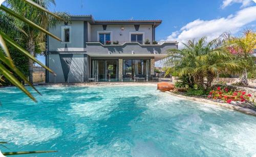 a swimming pool in front of a house at Villa Joel in Fontane Bianche