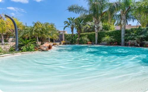 a large swimming pool in a yard with palm trees at Villa Joel in Fontane Bianche