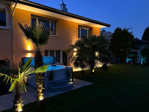 a house with a backyard with palm trees and lights at Residenza San Remy Hundefreundliche Ferienwohnung mit Whirlpool in Unterkulm