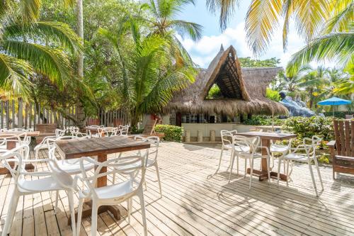 a patio with tables and chairs and palm trees at Cabañas Aqua Blue Coveñas in Coveñas