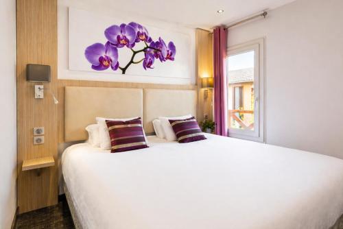 a bedroom with a large bed with purple flowers on the wall at FH Confort Hotel Orléans Co'met in Orléans