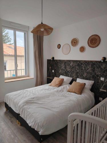 a bedroom with a large white bed with two pillows at Le p'timyno in Moncoutant