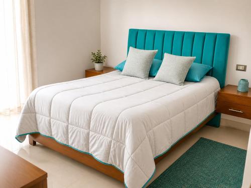 a bedroom with a large bed with a blue headboard at Tarija Premium Stay Apartamento Premium in Tarija
