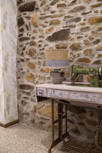 a sewing machine on a table with a stone wall at Casa da Goreti in Armamar