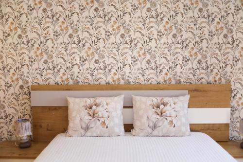a bed with two pillows in a bedroom with a wallpaper at Casa da Goreti in Armamar