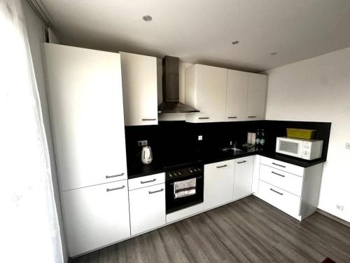 a kitchen with white cabinets and a stove top oven at STAY - Seeblick Apartment in Friedrichshafen