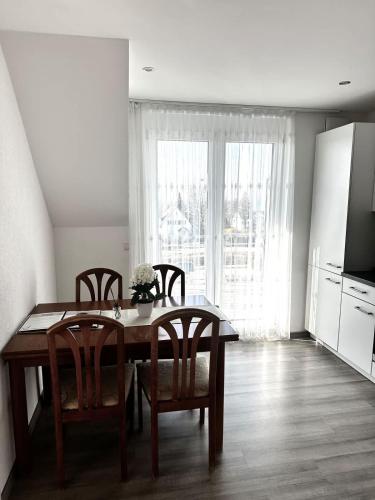 a dining room with a table and chairs and a kitchen at STAY - Seeblick Apartment in Friedrichshafen