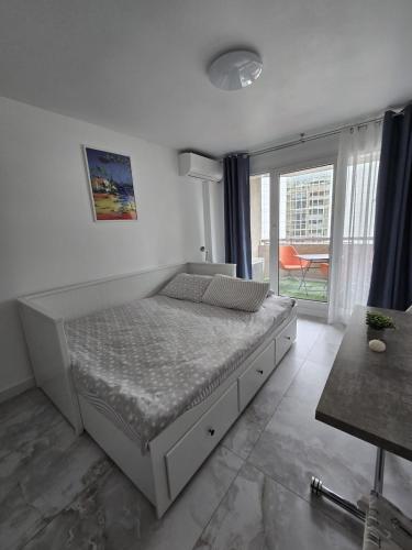a white bedroom with a bed and a balcony at Cozy Seaside Studio with Private Parking in Nice