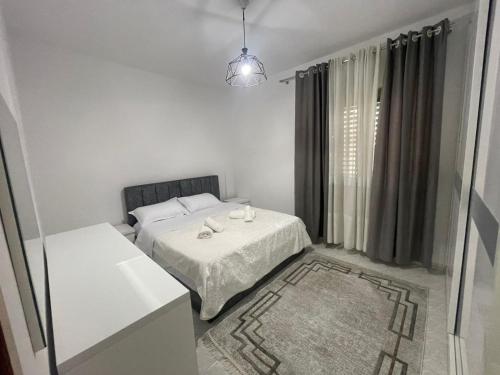 a white bedroom with a bed and a window at Dedi Apartment 2 in Shkodër