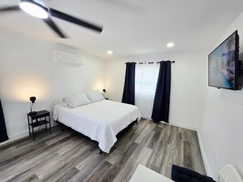 a white bedroom with a bed and a tv at Cozy Full Home Experience in Tampa