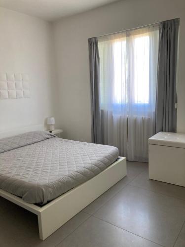 a white bedroom with a bed and a window at B&B Numero Uno in Bisceglie