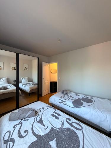 a bedroom with two beds and a mirror at Magnolia58 in Pontault-Combault