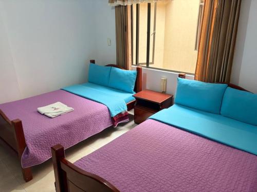 two beds in a room with purple and blue at Hotel Manhattan City in Duitama