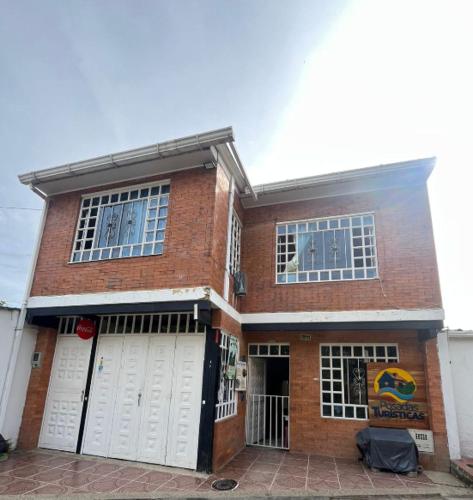 a brick house with two white garage doors at Cachipay panche in Cachipay