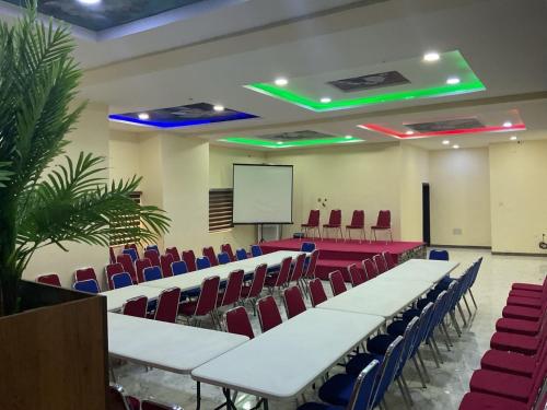 a lecture hall with white tables and chairs and a screen at The Tusk Hotel in Kuje