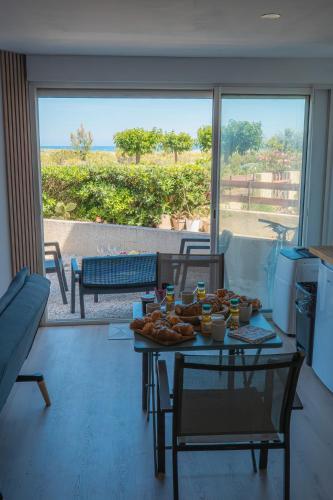 a living room with a table with food on it at Le Refuge Marin - Vue Mer - Accès direct Plage - Terrasse - Climatisation - Place de Parking in Leucate-Plage