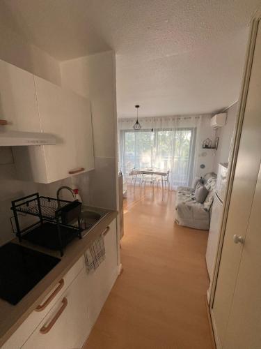 a kitchen with white cabinets and a dining room with a table at Studio cabine Canet Plage Parking in Canet-en-Roussillon