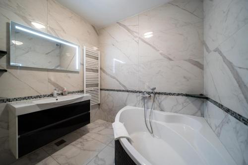 a white bathroom with a tub and a sink at Apartments Bajcic in Rab