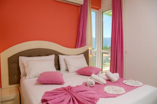 a bedroom with a bed with pink pillows and a window at Hotel Garden in Vlorë