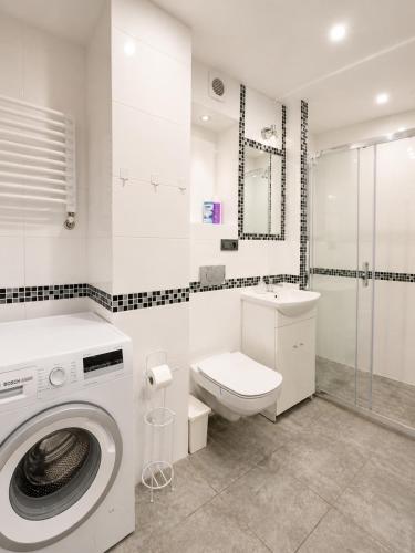 a white bathroom with a washing machine and a toilet at Centrum Warszawy - City Center the best places, metro Centrum & Świętokrzyska, partial view of the Palace of Culture, self check-in, AC, optional breakfest in Warsaw