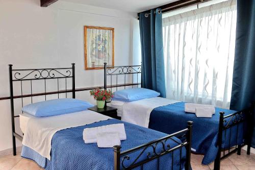 a bedroom with two beds with blue sheets and a window at Balcone sul Vesuvio in Vico Equense