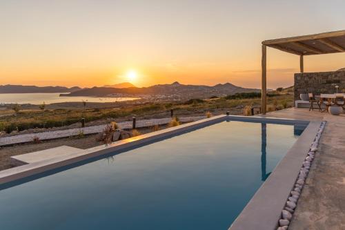 a pool with a view of the ocean at sunset at Villa Nabia by Milos Concierge in Adamantas
