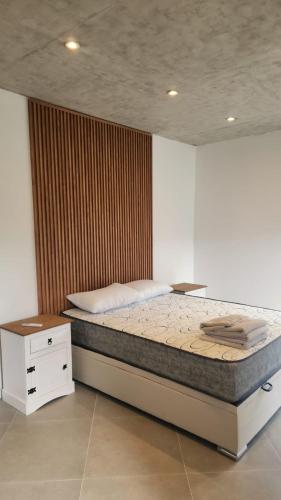 a bedroom with a bed and a wooden wall at lazy beach in Punta del Este